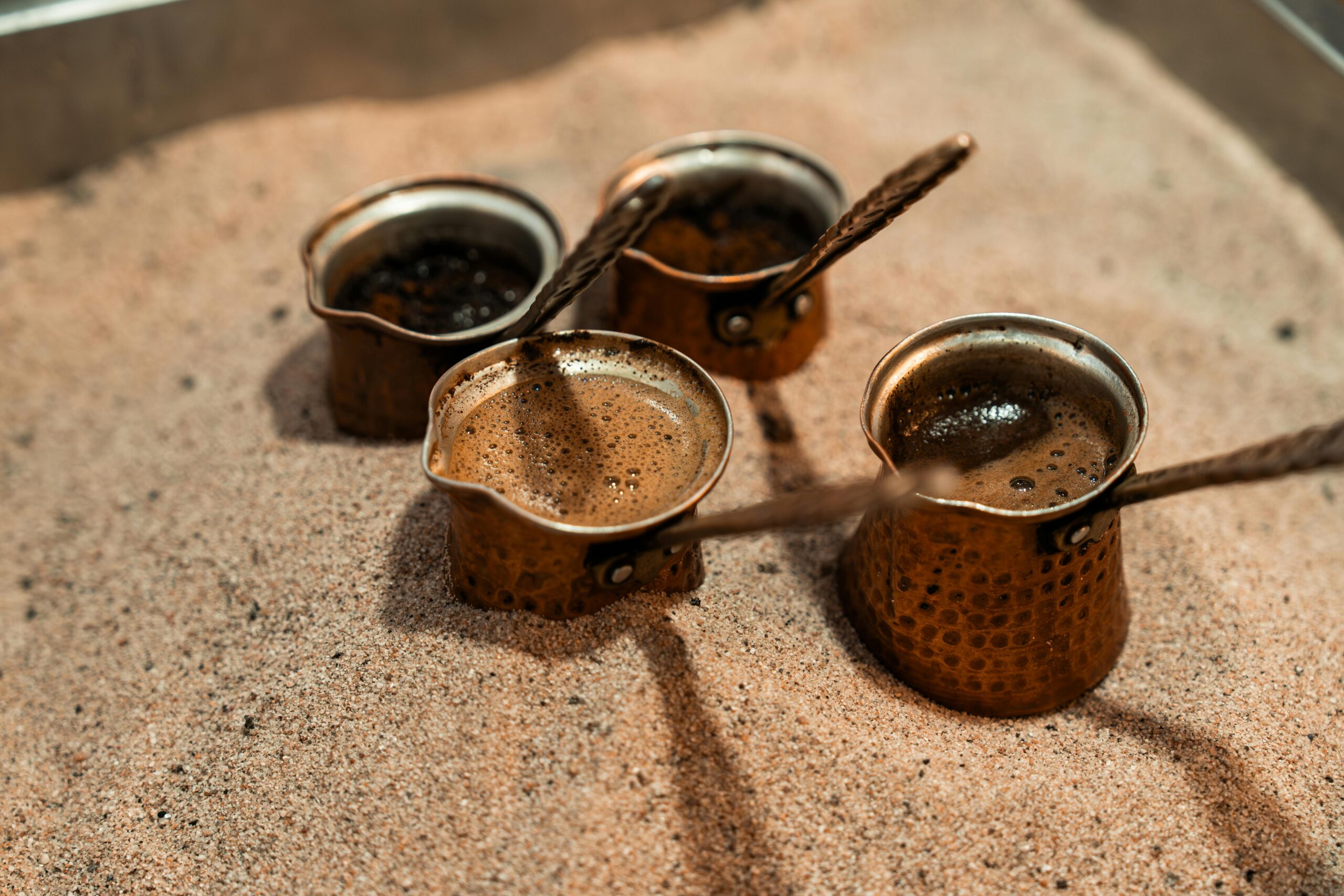 Café turco servido en cezve de cobre con tazas decoradas y fondo rústico.