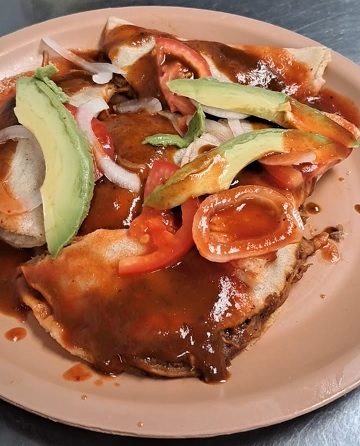 Tacos mineros michoacanos servidos con mole, papa y carne, una receta tradicional de más de 75 años.