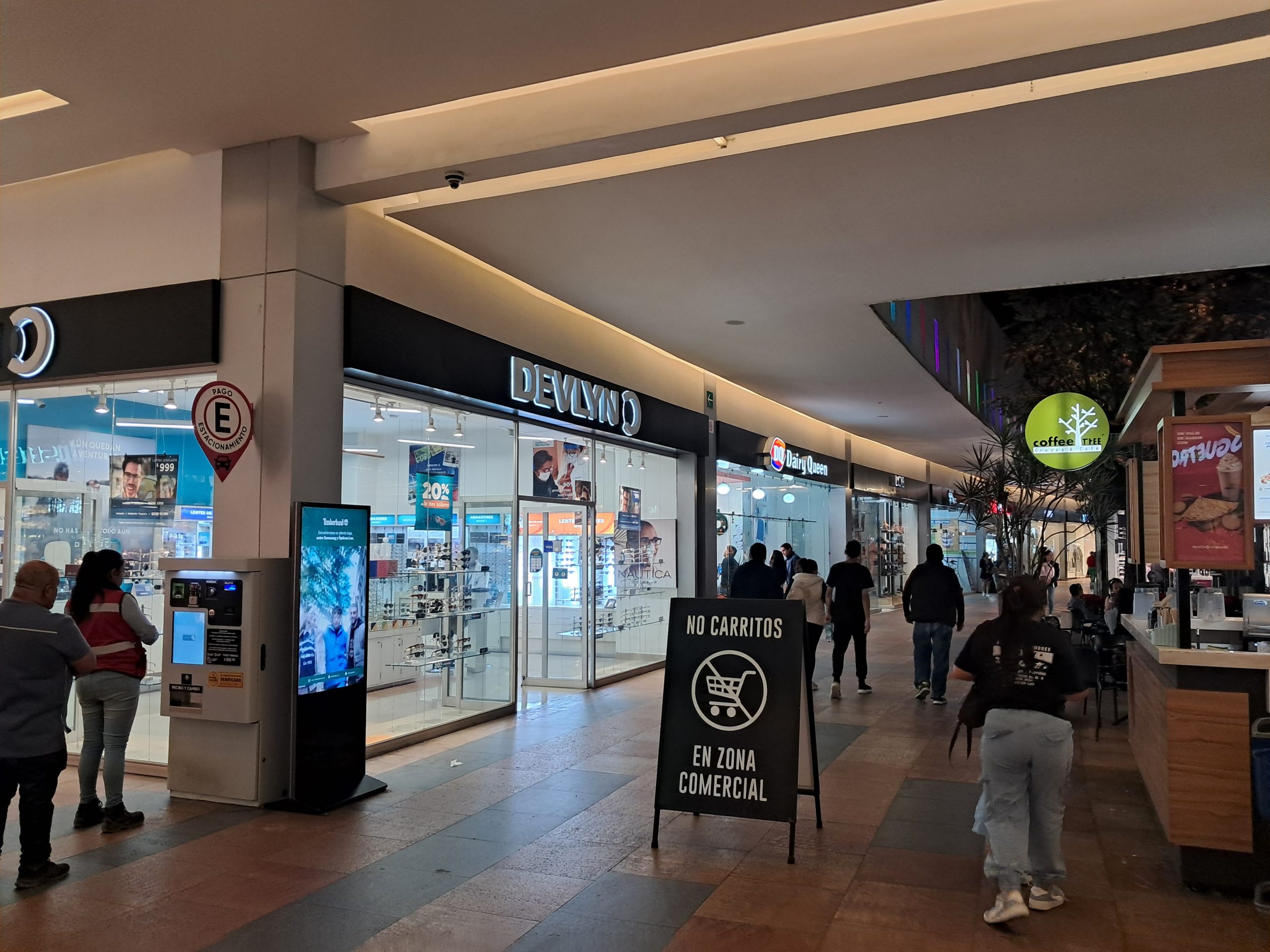 Pasillos interiores iluminados y amplios con diversas tiendas en Plaza Ágora Uruapan