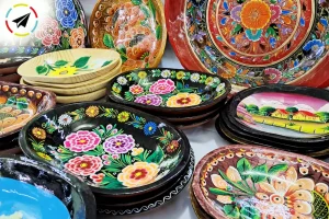 Bateas de maque o laca tradicional en el Tianguis Artesanal de Uruapan, Michoacán, piezas de madera decoradas con diseños florales y fondo negro brillante.