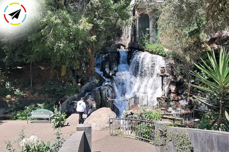 Cascada en el Parque Lineal La Camelina, Uruapan, con agua cayendo entre piedras y vegetación.