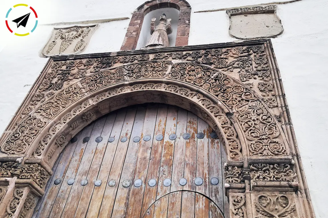 Puerta de la Capilla del Santo Sepulcro en La Huatápera de Uruapan, Michoacán. Portada del siglo XVI con arco de alfiz ornamentado con relieves, dos escudos de la Orden Franciscana y una escultura de San Francisco sobre la entrada.