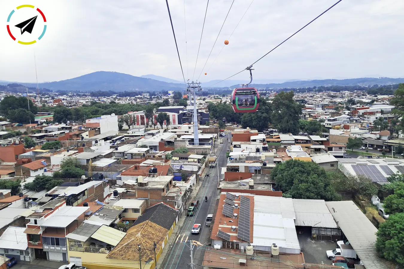 Vista de la ciudad de Uruapan desde la cabina del teleférico, con edificios y calles extendiéndose al fondo.