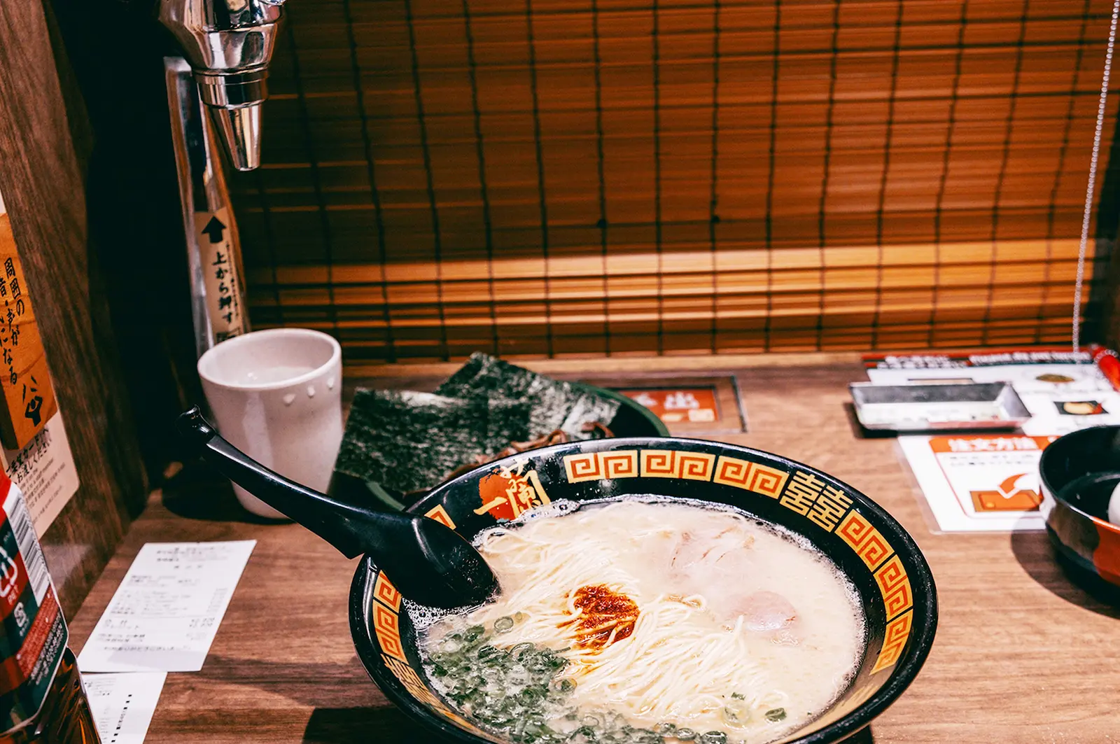 Puesto individual de Ichiran Ramen en Japón, con separadores de madera que aíslan al comensal para que se concentre en su comida sin distracciones.