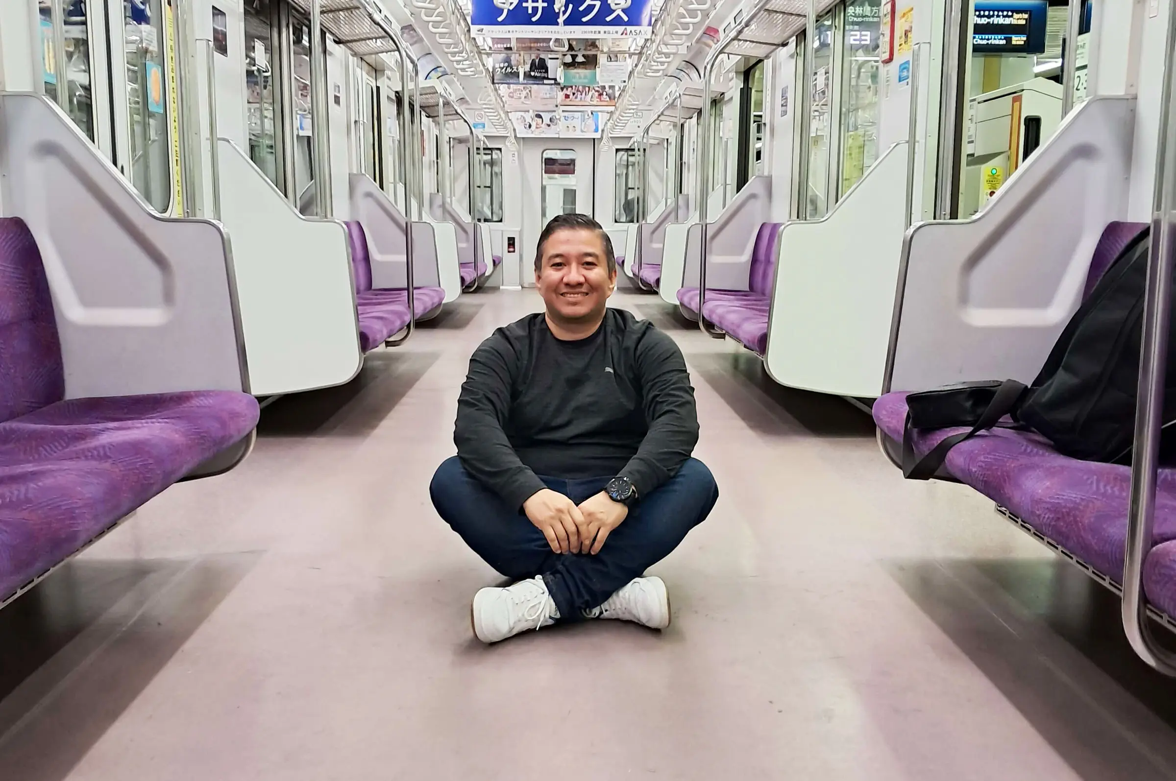 Persona sentada sola en el piso de un vagón del metro de Tokio, Japón, con el interior iluminado y los asientos vacíos a su alrededor.
