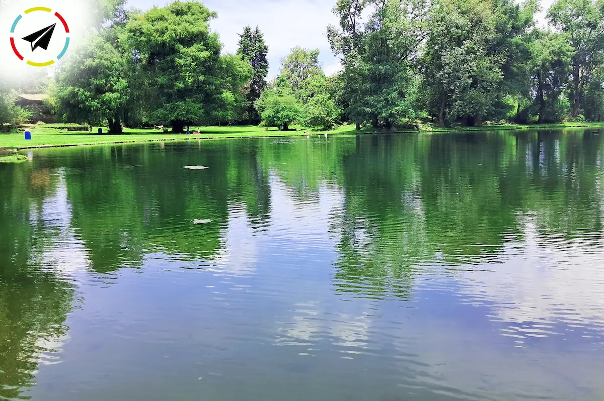 Vista del espejo de agua de la Presa Santa Catarina en Uruapan, también conocida como Presa de Caltzontzin, rodeada de árboles y vegetación, ideal para la fotografía al atardecer